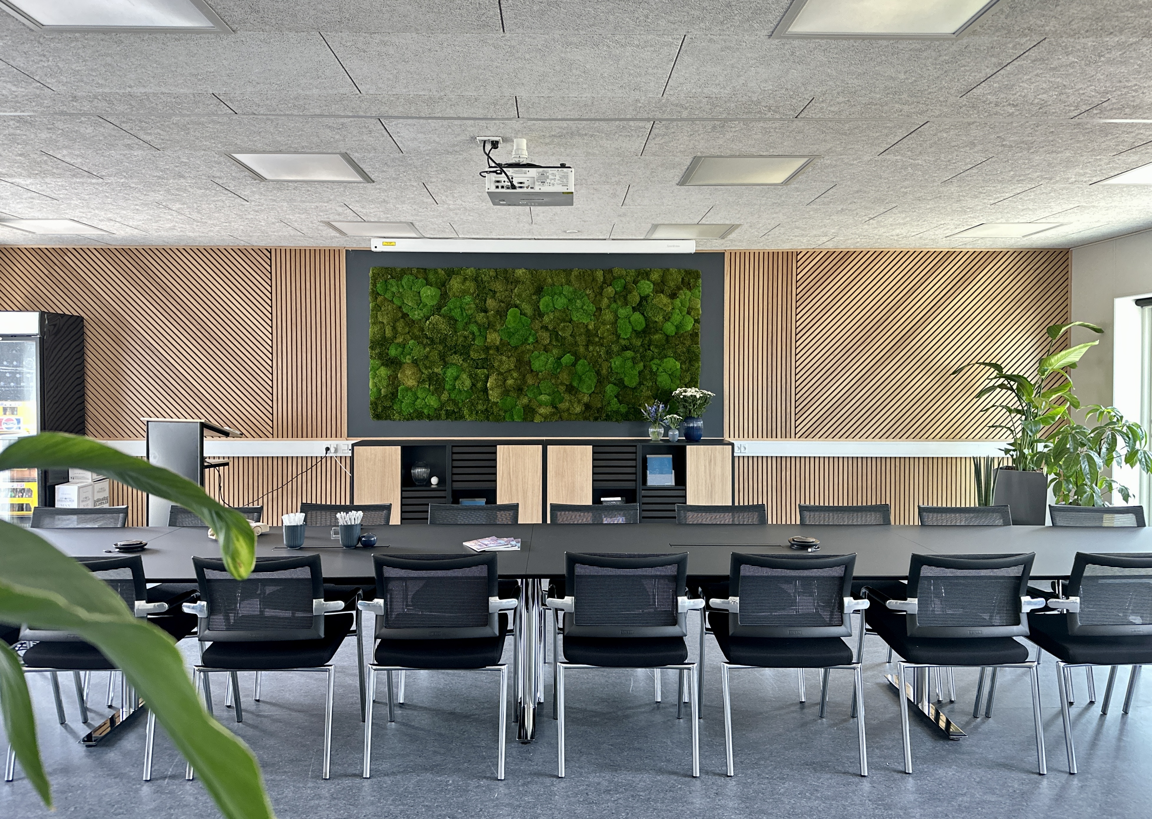 En kontorarbejdsplads med lyse møbler og grønne planter giver den bedste indretning
